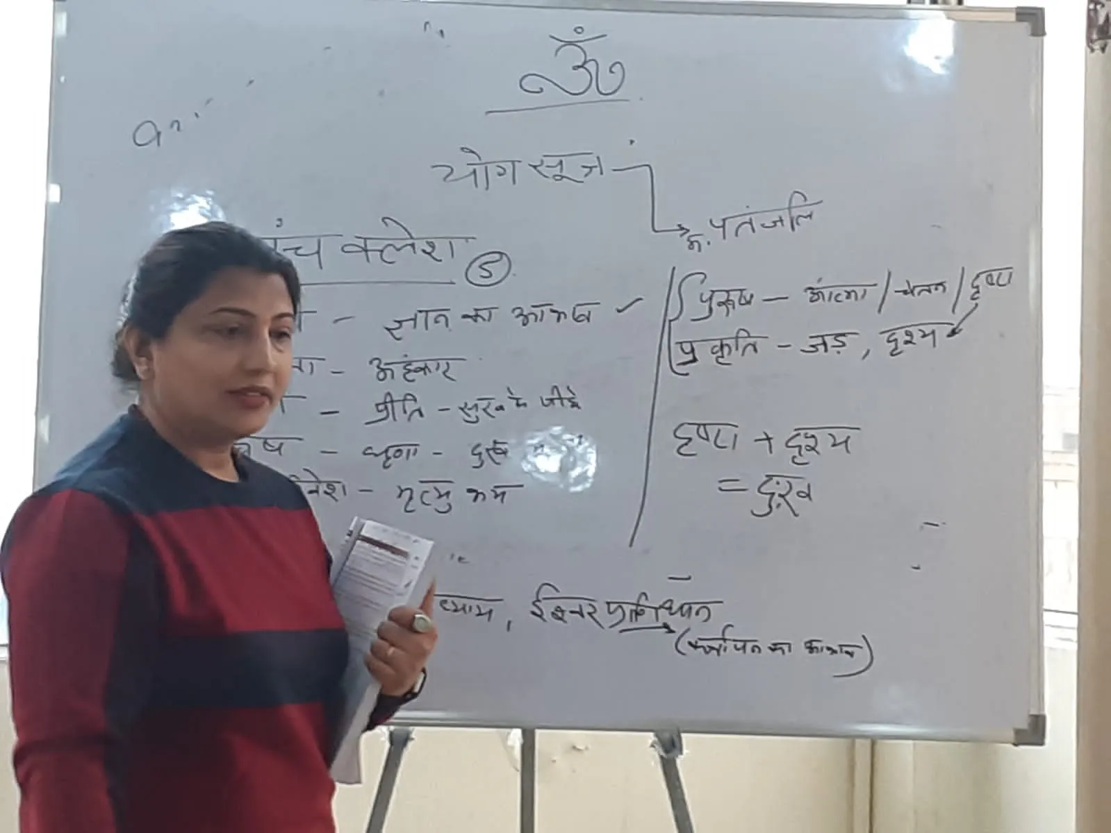 A TPNF teacher leading a class beside a whiteboard of handwritten Hindi notes.