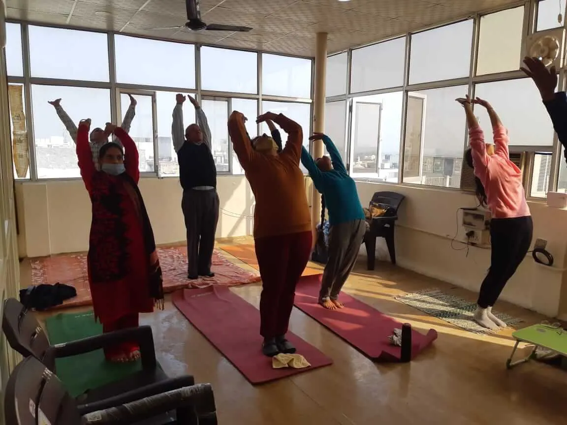 Participants stretching to one side with arms overhead during a TPNF wellness session.